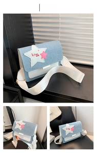Detail view of denim and white leather crossbody bag with star patch and wide strap