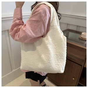 Close-up of a white pleated tote bag showing the unique textured fabric on a shoulder