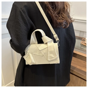 Detail of cream canvas crossbody bag with artistic knotted layers and silver hardware