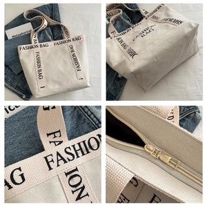 Close-up of the beige canvas tote bag showing fashion text, zipper, and thick texture