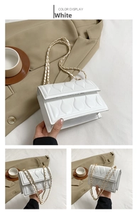 Detail of white quilted crossbody bag with teardrop texture and gold chain strap