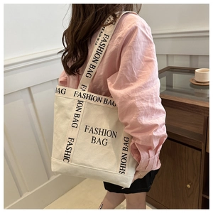 Canvas tote bag with black letter printed straps shown on model in a modern room