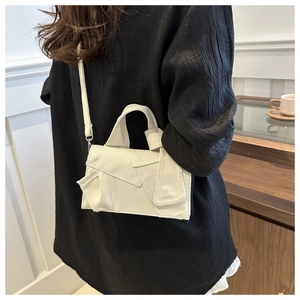 Detail view of white canvas crossbody bag with unique deconstructed patchwork design