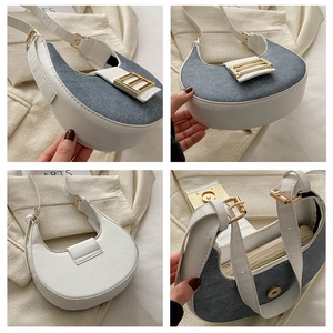 Detail view of denim and white faux leather half-moon bag with gold metal buckle closure