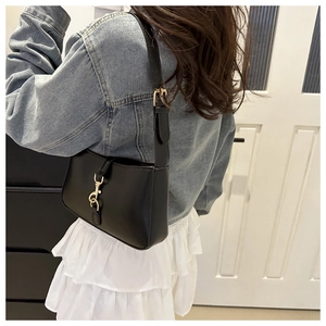 Detail of black baguette bag featuring gold lobster clasp and adjustable shoulder strap