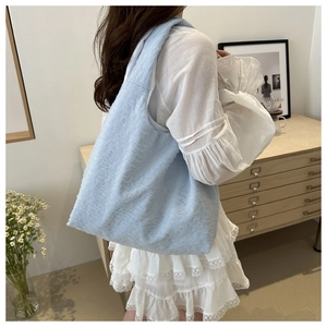 Detail of light blue pleated tote bag with textured lace fabric on model with white dress