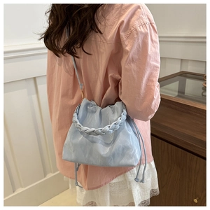 Detail of light blue cloud bag with braided handle and soft pleats on pink shirt