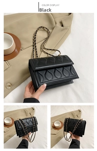 Detail of black quilted crossbody bag with teardrop texture and gold chain strap