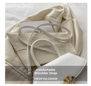 Détail d'un sac à main en cuir blanc avec fermoir doré semi-circulaire et bandoulière fine