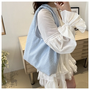 Detail of light blue pleated shoulder bag with textured fabric shown on a female model