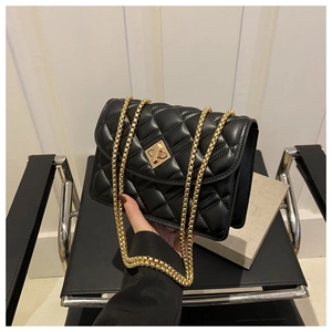 Detail of black quilted leather handbag featuring gold metal chain and diamond lock