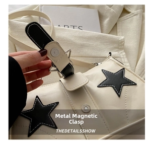 Detailed macro view of the magnetic metal clasp closure on the star-patterned underarm bag