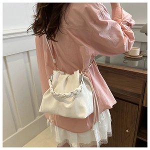 Lifestyle shot of a white pleated cloud bag with a braided handle and crossbody strap