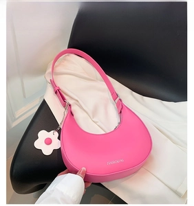 Detail view of pink leather half-moon bag with white flower charm and adjustable strap