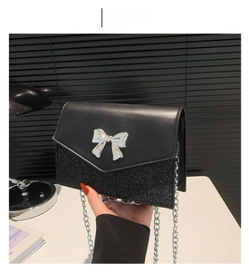 Dettaglio della borsa nera in pelle e glitter con fiocco in metallo argento e catena