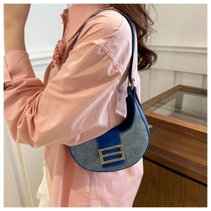 Detail view of crescent shoulder bag featuring navy faux leather and denim patchwork design