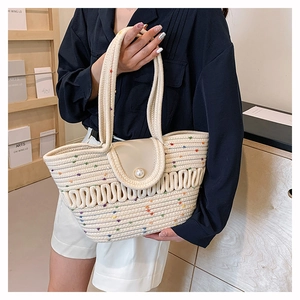 Détail du sac fourre-tout tissé crème avec des taches colorées et un grand fermoir perle