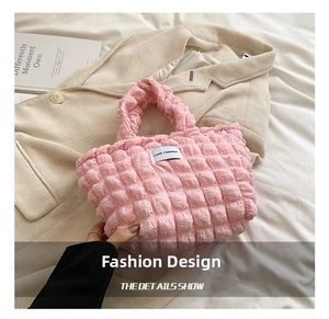 Close-up of pink quilted puffy shoulder bag featuring a soft waffle texture and fabric label
