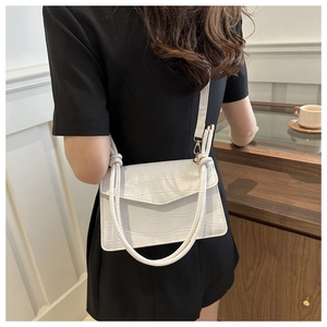 Detail of white crocodile embossed shoulder bag with unique knotted strap design on a model