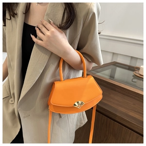 Sac à main bandoulière orange vif avec fermoir métallique éventail porté par modèle