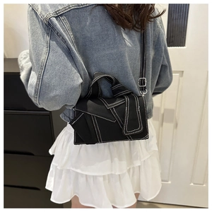 Close-up of black denim crossbody bag with white contrast stitching on model outfit