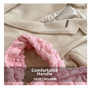 Detailed close-up of the comfortable pink pleated handle on a cloud bubble shoulder bag