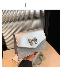 Dettaglio borsa di paillettes argento con fibbia a fiocco metallico e catena elegante