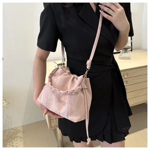 Close-up of pink pleated cloud bag with woven handle and drawstring design worn by model