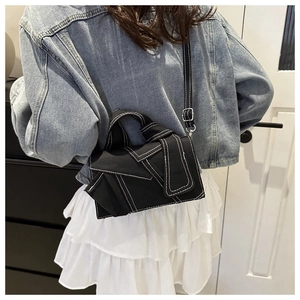 Rear view of a black canvas crossbody bag with white contrast stitching on a model