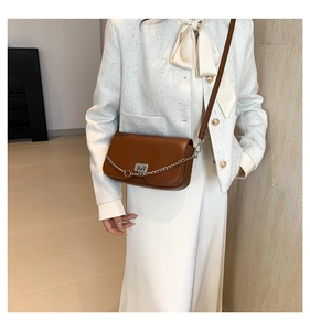 Brown faux leather crossbody bag detail with silver chain and metal twist lock