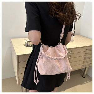 Pink pleated drawstring bucket bag with thick braided handle on female model