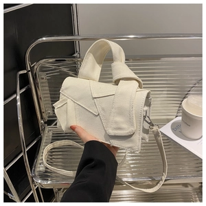 Detail of cream canvas crossbody bag with unique knot folding design and metal stand view