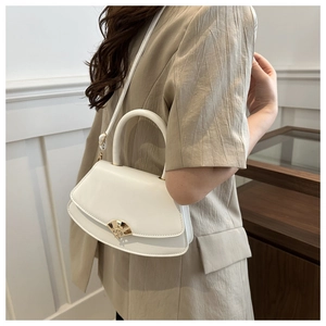 Détail d'un sac demi-lune blanc en cuir avec un fermoir en métal doré en forme d'éventail