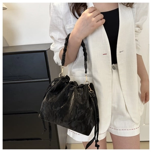 Close-up of black drawstring bucket bag with thick woven handle and gold rings