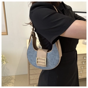 Macro detail of crescent denim hobo bag with contrast leather trim and golden metal buckle