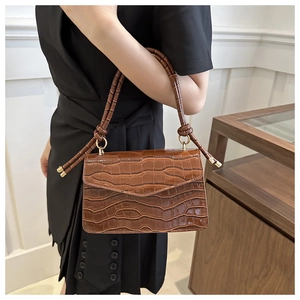 Detailed shot of brown crocodile embossed leather with gold ring and knot handle design