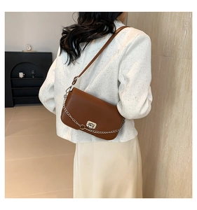 Back view of a classic brown leather crossbody bag with silver chain on a model
