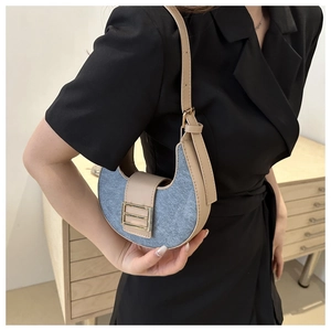 Detail of crescent shoulder bag featuring blue denim fabric and beige leather trim contrast