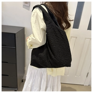 Detailed view of black bubble texture fabric shoulder bag showing high capacity on model