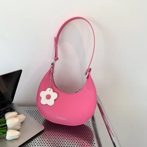 Pink crescent hobo bag in matte leather with floral charm on metallic table