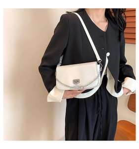 Detail shot of the cream-colored square bag with silver clasp and metallic chain decoration
