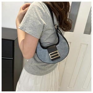 Detail of grey denim crescent shoulder bag with black trim and gold metal buckle