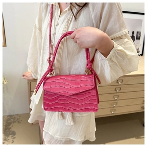 Macro detail of magenta crocodile pattern bag with golden hardware and tassel detail