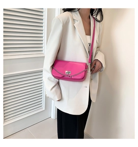 Fashionable bright pink leather crossbody bag shown on model with white blazer