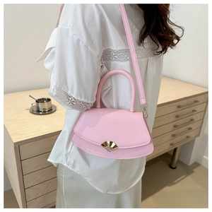 Sac bandoulière rose chic avec fermoir éventail doré porté par un mannequin