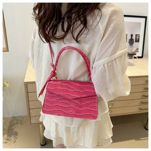 Detail view of pink crocodile pattern texture and metallic flip closure on small bag