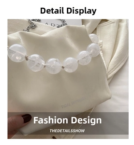 Detail of white lychee leather bag featuring a chunky marbled bead handle and chain strap
