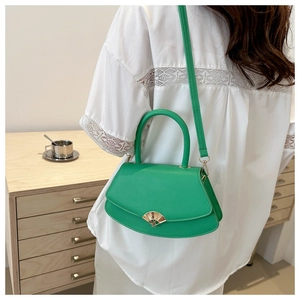 Détail du sac bandoulière vert semi-ovale avec fermoir doré en forme d'éventail et cuir