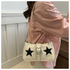 Détail du sac sous le bras crème avec étoiles noires brodées et boucle argentée en étoile