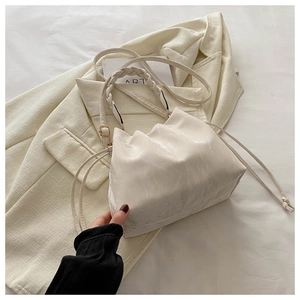 Detail of cream chain bucket bag featuring woven handle and drawstring closure